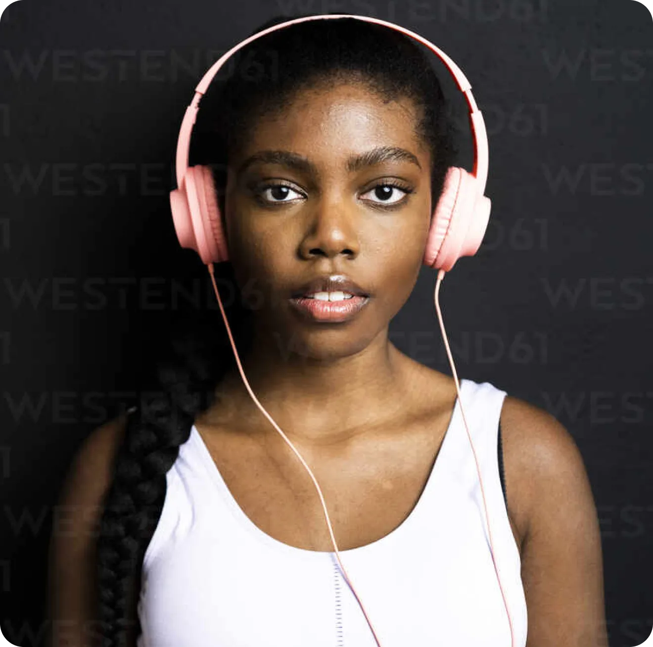 Young woman wearing pink headphones, engaging with audio content, representing Yuno's enriching and accessible learning experience