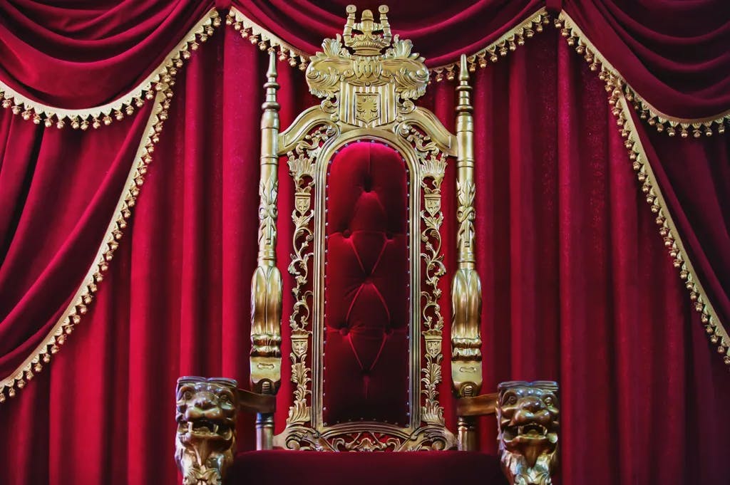 Teil des roten königlichen Stuhls auf rotem Hintergrund. Ein Ort für einen König. Thron