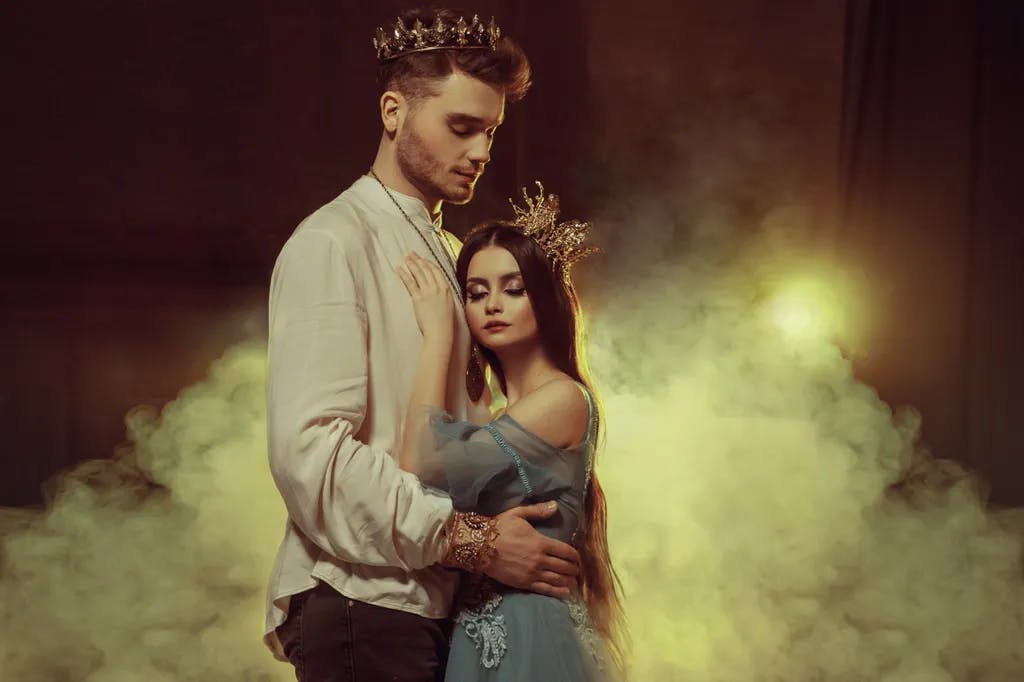 Fantasy-Paar umarmt in dunklem Raum voller weißer Rauch. Bild von Liebhabern - König und Königin.